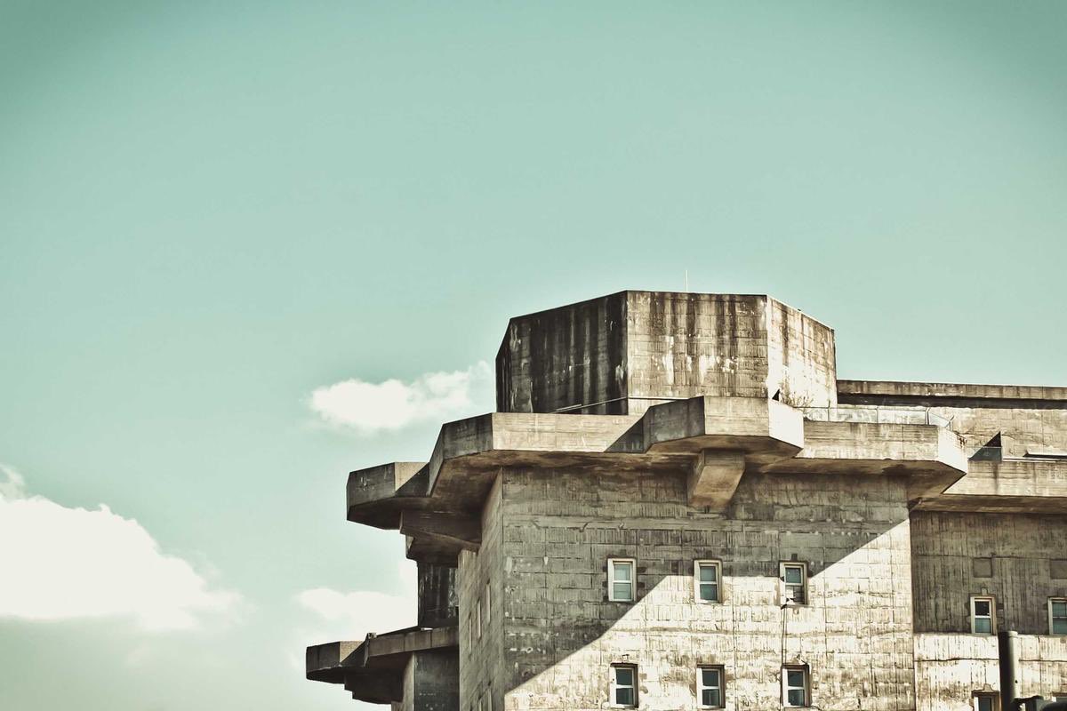 Brutalist board-formed concrete mass against a pale sky