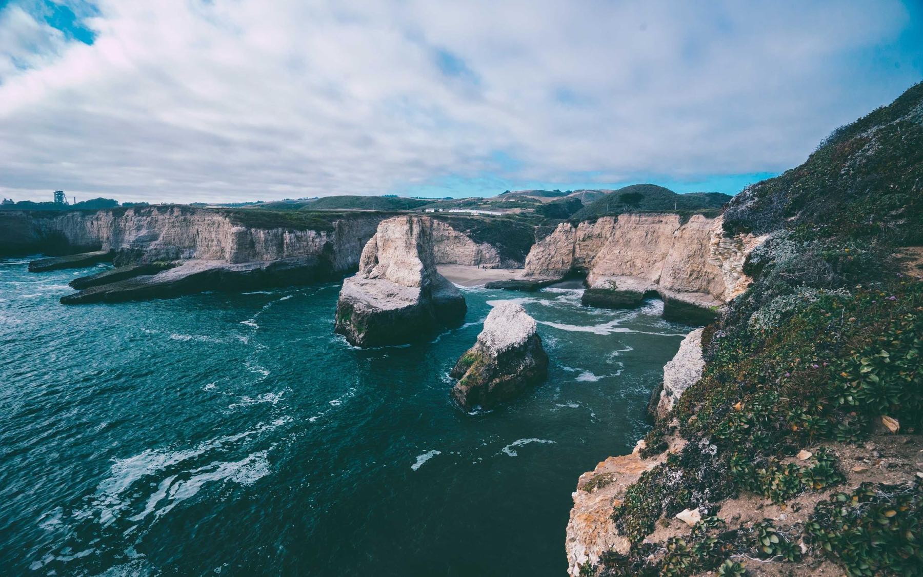 Rugged coastal cliffs meeting a teal Pacific sea